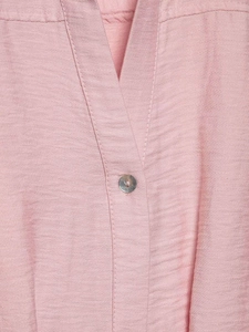 Detailed close-up of pink V-neck collar with shell button and textured fabric weave