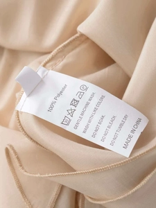 Detail of the washing label showing 100% polyester fabric and care instructions for the skirt