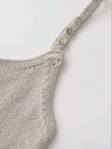 Detailed close-up of cream knit camisole with decorative buttons on wide shoulder straps