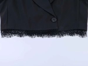 Detail of black cropped blazer featuring eyelash lace hem and single round button