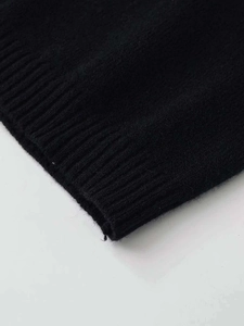Dettaglio del top in maglia nera con trama fine e polsini a coste di alta qualità