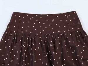 Detail view of high-waist dark brown polka dot wide-leg trousers with pleated waistline