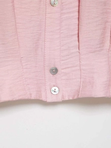 Close-up of pink woven shirt featuring shimmering shell buttons and neat stitching