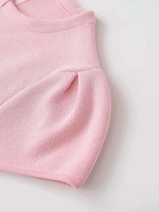 Detail of pink knit top featuring stylish puff sleeves and textured pleated shoulders