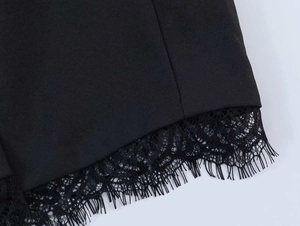 Detailed view of the black blazer hem featuring delicate eyelash lace trim and woven texture
