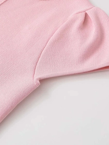 Close-up of pink knit top detailing fine vertical texture and pleated puff sleeve seams