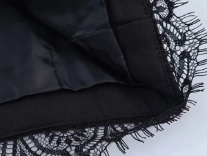 Detail shot of black floral lace trim with eyelash fringe on a chic summer suit