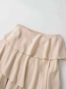 Detail of elegant beige ruffled skirt fabric showing soft texture and draping flow