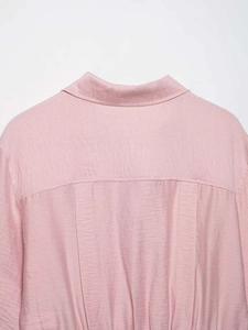 Detail of light pink shirt back featuring textured fabric and vertical pleats design
