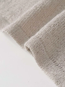 Detail shot of beige ribbed knit fabric showing intricate texture and hollow patterns