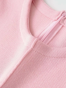 Detailed close-up of pink knit round neck with smooth back zipper closure and stitching