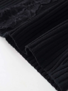Detail of ribbed knit fabric texture with delicate lace trim on black v-neck top