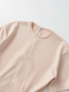 Detail of light beige pleated midi dress featuring a round neckline and fine twill texture