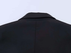 Detail shot of black lace patchwork blazer neckline showing premium woven texture