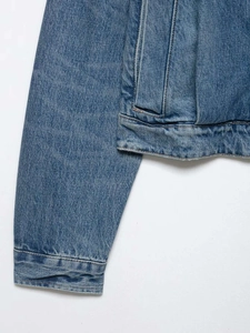 Detail view of stitched hem and cuff on a vintage blue wash denim jacket for women