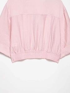 Detail of pink blouse showing pleated back design and elasticated waist hem texture