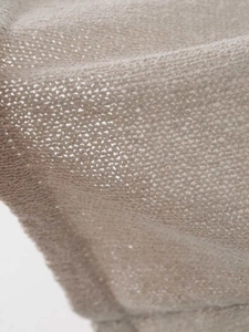 Macro shot of breathable beige knitted fabric with soft texture and refined stitching detail