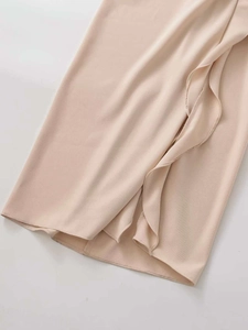 Close-up of champagne pleated midi dress hem with delicate ruffle details and texture