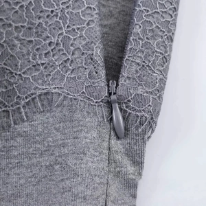 Nahaufnahme eines grauen Mini-Kleides mit Spitzenbesatz, Mesh-Mustern und verdecktem Reißverschluss