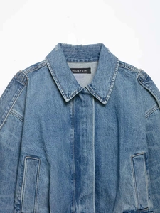 Detail of vintage blue washed denim jacket collar with epaulettes and branding label