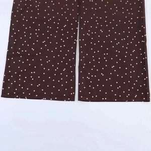 High-waisted brown wide-leg pants with white polka dots and stitched hem detail