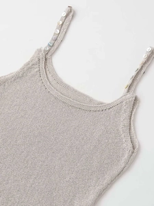 Detail of knit camisole showing colorful buttons on straps and delicate openwork neckline