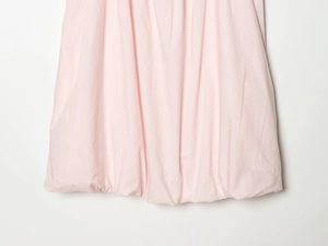 Detail shot of a light pink mini dress featuring a voluminous bubble hem design