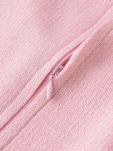 Detail of pink knit fabric showing fine texture and a teardrop-shaped invisible zipper