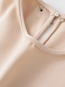 Detailed view of beige pleated midi dress neckline with V-cutout and button closure