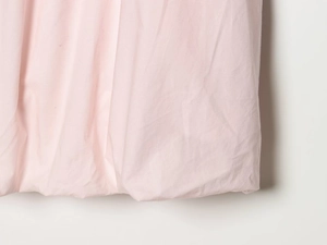 Detailed macro view of light pink fabric texture and soft pleated hem for mini dress