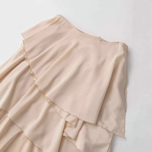 Elegant apricot satin midi skirt featuring layered ruffled hem and smooth draped fabric