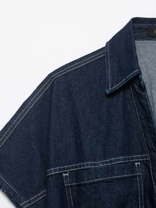 Detailed close-up of dark blue denim shirt collar featuring contrast white stitching