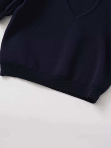 Detail of navy V-neck knit sweater showing smooth jersey stitch and ribbed hem texture