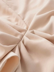 Close-up of beige midi dress featuring detailed pleated fabric and twill texture