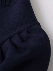 Macro shot of navy blue knit top showing ribbed neckline and pleated shoulder details