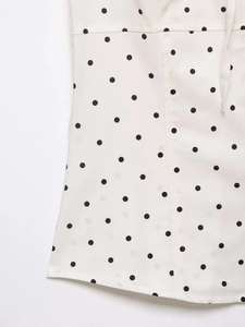 Detailed close-up of the polka dot fabric texture and sewing lines on a white shirt
