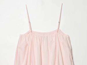 Detail of light pink mini dress showing adjustable spaghetti straps and pleat texture