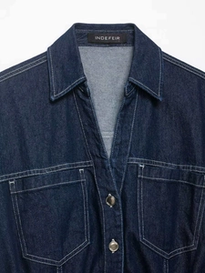 Detail of dark blue denim shirt collar featuring contrast white stitching and metal buttons