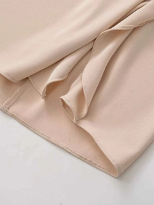 Close-up of beige midi dress hem showing precise stitching and smooth woven fabric texture