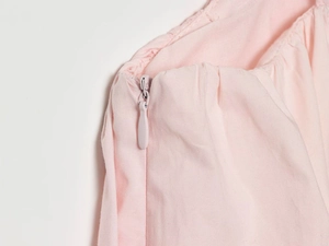 Detailed macro shot of high-quality invisible side zipper on pink nylon mini dress