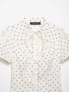 Detail of white polka dot short sleeve shirt with ruffle collar and ribbon tie