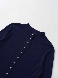 Dettaglio del cardigan in maglia blu scuro con bottoni argento e collo increspato