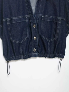 Detail of blue denim shirt with utility pockets, contrast stitching and drawstring hem