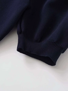 Detailed close-up of dark blue ribbed cuffs on a summer knit sweater with heart cut-outs
