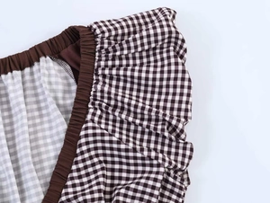 Detail of checkered blouse featuring elastic ruffled cuffs and contrast brown piping