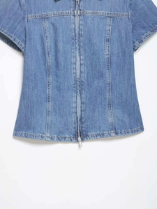 Detailed view of blue denim short sleeve shirt featuring front zipper and stitched seams