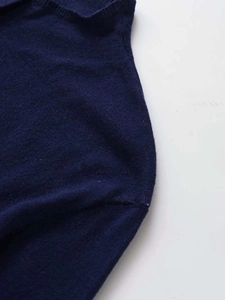 Dettaglio cardigan in maglia blu scuro con cuciture sulle spalle e bordo a coste