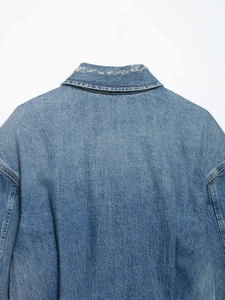 Close-up of retro washed denim jacket collar featuring unique distressed ripped details