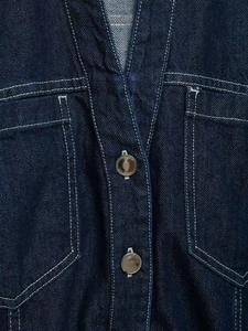 Detail of dark blue denim dress with white contrast stitching and metallic buttons