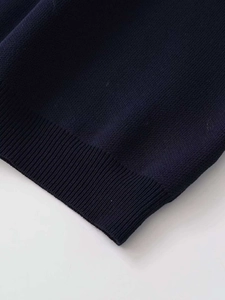 Macro detail of the navy blue ribbed knit hem and texture on this women's sweater